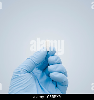Il concetto di cura Del Vaccino di Coronavirus Covid-19. Mano In Gomma Chirurgica Blu Glove Tenendo Una Singola Capsula Bianca Pill Foto Stock