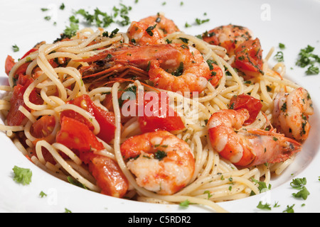 Germania, Close up di spaghetti con scampis fritti in olio aromatizzato al peperoncino, pomodoro e basilico Foto Stock
