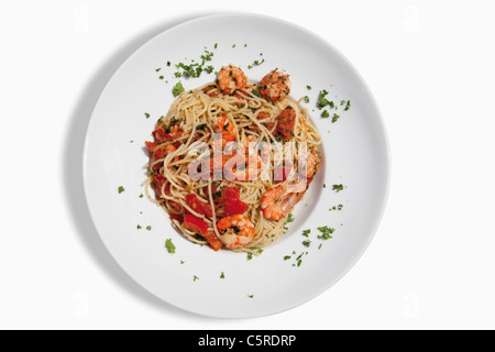 Close up di spaghetti con scampis fritti in olio aromatizzato al peperoncino, estratto di pomodoro e le erbe contro uno sfondo bianco Foto Stock