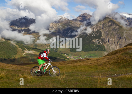 L'Italia, Livigno, vista di donna equitazione mountain bike Foto Stock