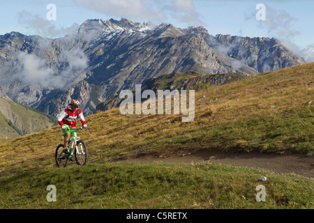 L'Italia, Livigno, vista di donna equitazione mountain bike in salita Foto Stock
