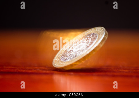 La filatura due pound coin su un tavolo di legno con uno sfondo nero Foto Stock
