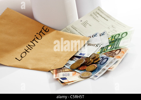 Scheda fiscale, Euro monete e banconote in euro nel pacchetto salariale Foto Stock