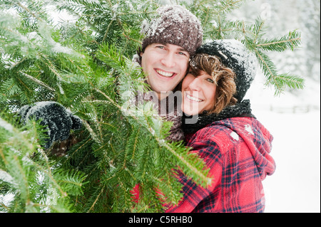 L'Austria, paese di Salisburgo, Flachau, giovane uomo e donna azienda albero di natale Foto Stock