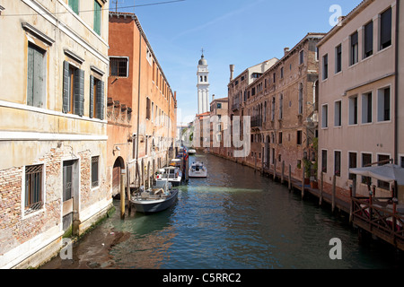 Venezia, gli stretti canali tra i vecchi edifici storici. I fiori sul davanzale della finestra. Barre di protezione su Windows. Foto Stock