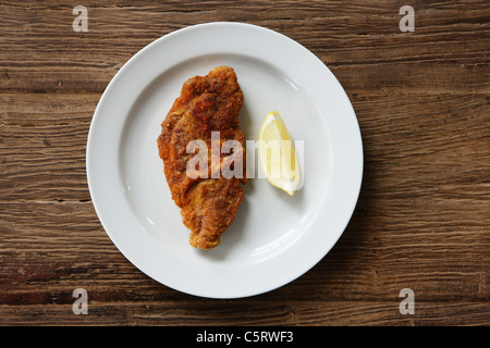 La Wiener Schnitzel con fettina di limone su sfondo di legno, close up Foto Stock