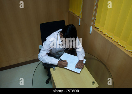 Giovane uomo indiano al lavoro in cabina di Office Foto Stock