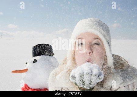 In Germania, in Baviera, Monaco di Baviera, giovane donna lavori di soffiaggio della neve Off mano, ritratto Foto Stock