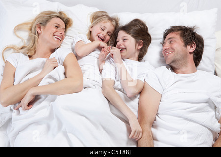 In Germania, in Baviera, Monaco di Baviera, Famiglia giacente in letto, ridendo Foto Stock