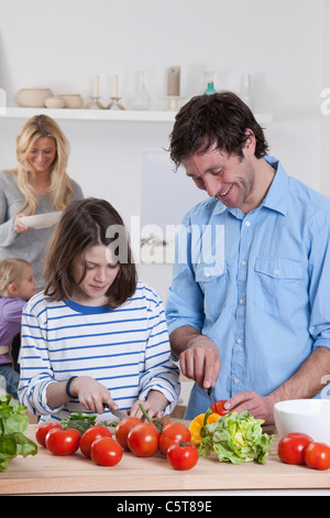 In Germania, in Baviera, Monaco di Baviera, figlio preparare insalata con padre, madre e figlia in background Foto Stock