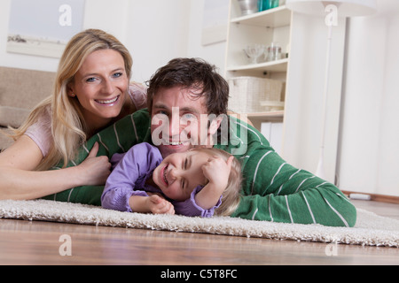 In Germania, in Baviera, Monaco di Baviera, Famiglia giacente su un tappeto, sorridente Foto Stock