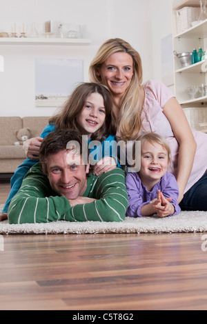 In Germania, in Baviera, Monaco di Baviera, Famiglia giacente su un tappeto, sorridente, ritratto Foto Stock