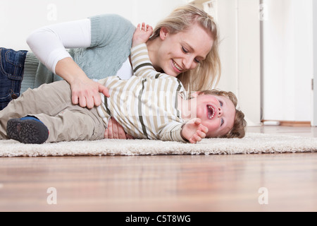 In Germania, in Baviera, Monaco di Baviera, madre e figlio giocando sul pavimento a casa Foto Stock