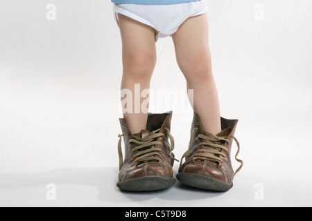 Bambino indossando scarpe di grandi dimensioni, sezione bassa Foto Stock