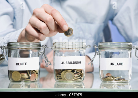 Persona messa Euro moneta in barattoli per conserve, close up Foto Stock