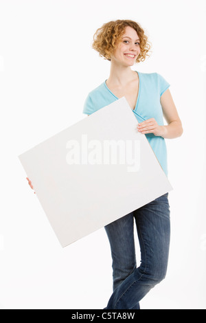 Giovane donna holding fustellato di cartone, sorridente, ritratto Foto Stock