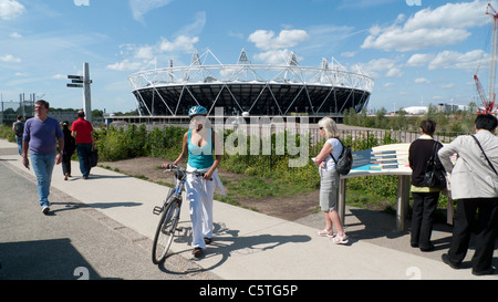 Giovane donna con mountain bike e casco su Greenway vicino al tubo di visualizzazione area con altri visitatori 2012 Olympic Stadium di Londra Inghilterra Foto Stock