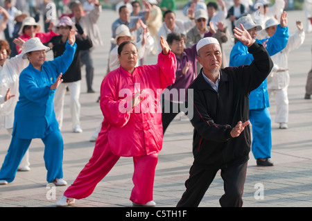 Seniors eseguire la mattina presto il Tai Chi, tra cui un uomo musulmano, nel parco cittadino, Xining, Provincia di Qinghai, Cina Foto Stock