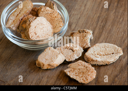 Essiccato galangal a fette, in capsula di vetro, fino a una cucina in legno superficie Foto Stock