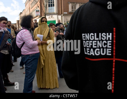 Una Donna vestita di un burqa sfida e affronta la difesa inglese League, durante il loro incontro di piccole dimensioni in Exeter City Center. Foto Stock