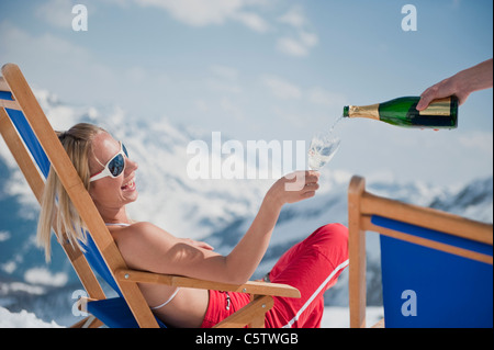 Bella donna mentire indietro nella neve sci da indossare abbigliamento e occhiali  da sole in una giornata di sole in montagna Foto stock - Alamy