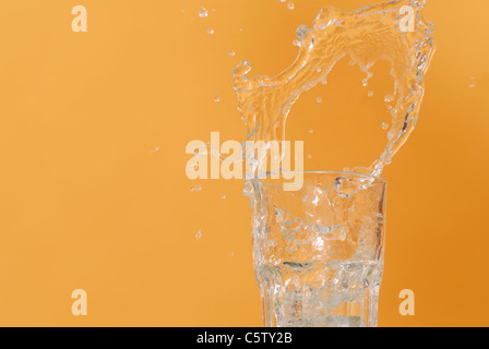 L'acqua versata in vetro, debordi, close up Foto Stock