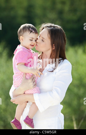 In Germania, in Baviera, madre baciando la sua bambina, sorridente Foto Stock