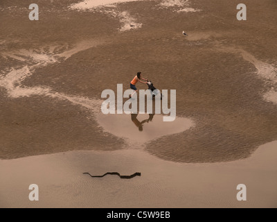 Giovane madre spingendo la PRAM in tutta Blackpool Beach Foto Stock