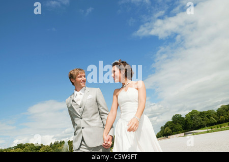 In Germania, in Baviera, la sposa e lo sposo passeggiate nel parco, tenendo le mani, sorridente, ritratto Foto Stock