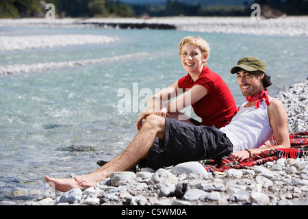 In Germania, in Baviera, TÃ¶lzer terra giovane coppia seduta sulla riva Foto Stock