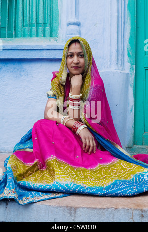 Una donna indiana pone di fronte a una delle tradizionalmente dipinte di blu delle case nella città di Jodhpur, in India nel Rajasthan Foto Stock