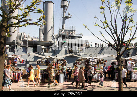 I turisti e le bancarelle di fronte al russo incrociatore Aurora, ex nave da guerra ora una nave museo di San Pietroburgo, Russia Foto Stock