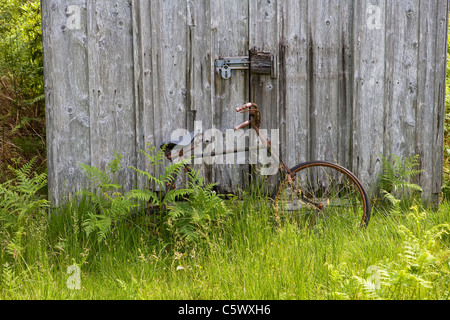 Rusty vecchia bicicletta da una capanna in legno, visto in Glen Etive, Scozia Foto Stock