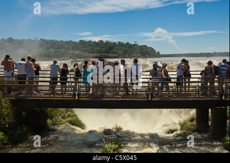 I turisti su una passerella che si affaccia l'Iguazu/Iguaçu falls, Provincia Misiones, Argentina Foto Stock