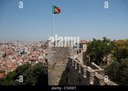 Le mura del castello di São Jorge portoghese con battenti bandiera di una parte superiore di una torre e una porzione di Lisbona Foto Stock
