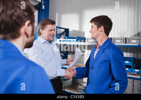 Germania, Neukirch, apprendista e istruttore stringono le mani, vista laterale Foto Stock