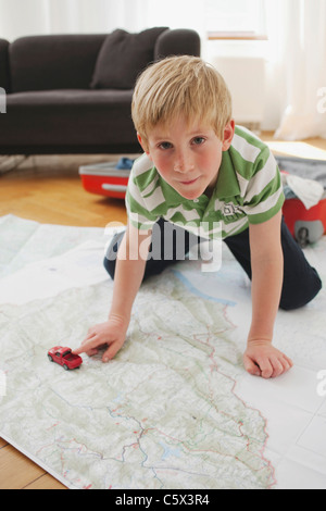 Germania, Lipsia, ragazzo (8-9) inginocchiato sulla mappa, ritratto Foto Stock