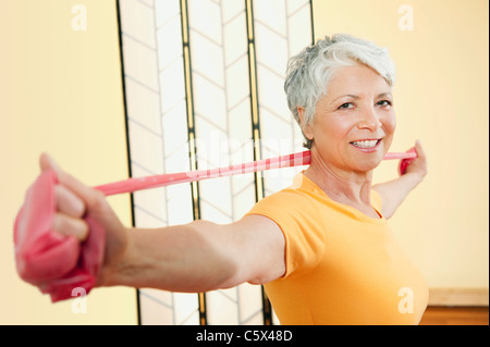 Senior donna esercita con fascia elastica, sorridente, ritratto Foto Stock