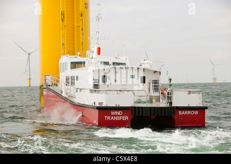 Un recipiente di alimentazione accanto ad una turbina eolica del Walney per centrali eoliche offshore project, off Barrow in Furness, Cumbria, Regno Unito. Foto Stock