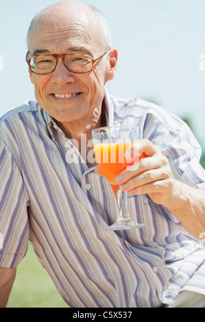 Spagna, Mallorca, Senior uomo con vetro con succo di arancia, ritratto Foto Stock