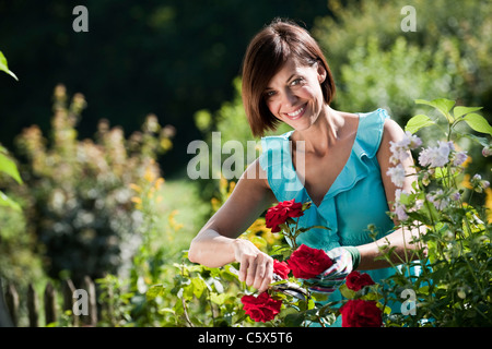 In Germania, in Baviera, Donna fiori di potatura in giardino Foto Stock