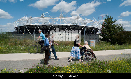 Persone che camminano con una sedia a rotelle e escursioni in bicicletta lungo la greenway passato il nuovo stadio Olimpico di Stratford East London Inghilterra England Regno Unito Foto Stock