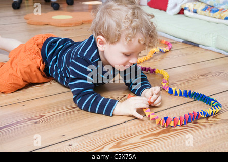 Germania Berlino, ragazzo (3-4) giacente sul piano, giocando con streamer Foto Stock