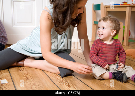 Germania Berlino, madre e figlio (2-3) seduto sul pavimento in legno, ridendo, ritratto Foto Stock