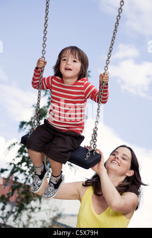 Germania Berlino, madre e figlio (3-4) al parco giochi su swing, ritratto, close-up Foto Stock