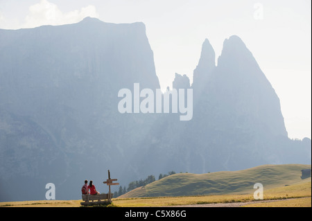 L'Italia, Alto Adige, Seiseralm, giovane seduto su un banco di lavoro, vista posteriore Foto Stock