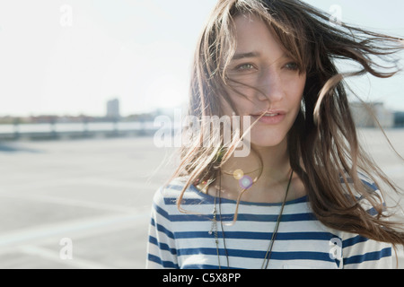 Germania, Berlino, giovane donna sul deserto parcheggio livello, ritratto, close-up Foto Stock