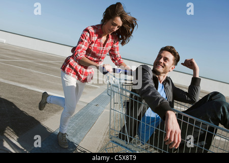 Germania, Berlino, giovane donna spingendo giovane uomo nel carrello Foto Stock