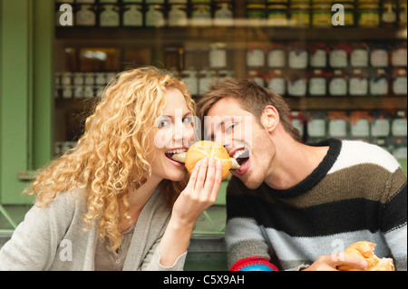 In Germania, in Baviera, Monaco di Baviera, giovane coppia al Viktualienmarkt avente uno snack, ritratto Foto Stock