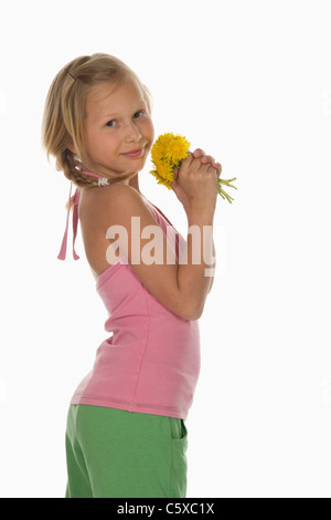 La ragazza (10-11) azienda fiori di tarassaco, vista laterale, ritratto Foto Stock